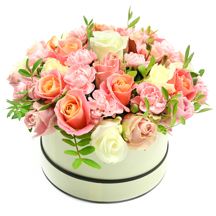 A luxuriously packed dome of roses and carnations sits within a classic round hatbox in soft cream, the box trimmed with two thin dark bands-one along the top rim and one near the base-providing a chic, tailored contrast to the pale container. The arrangement is a study in soft, romantic colour: large, velvety roses show warm coral-peach and apricot tones at their hearts that gently transition to blush pink and creamy ivory on outer petals, while clusters of frilly light-pink carnations fill in the negative space with a plush, ruffled texture. Narrow, elongated green foliage emerges intermittently, giving depth and a fresh, herbaceous lift to the palette. The hatbox's matte finish and the clean white background make every shade and petal-edge crisp under soft, natural light, and the subtle fragrance suggested by the image feels like a light, powdery perfume. As a local florist working around Enfield Wash, from Enfield Lock toward Ponders End and Hertford Road, we design this kind of composition to convey sincere affection-ideal for birthdays, anniversaries, a refined Valentine's gift, or simply to brighten someone's day. The craftsmanship is apparent in the rounded silhouette and the careful staging of bloom stages and foliage to create movement and balance. For customers seeking a premium, locally prepared gift, this is the sort of arrangement Flowers Enfield Wash often prepares for neighbourhood deliveries, chosen for its comforting presence and classic, timeless elegance.